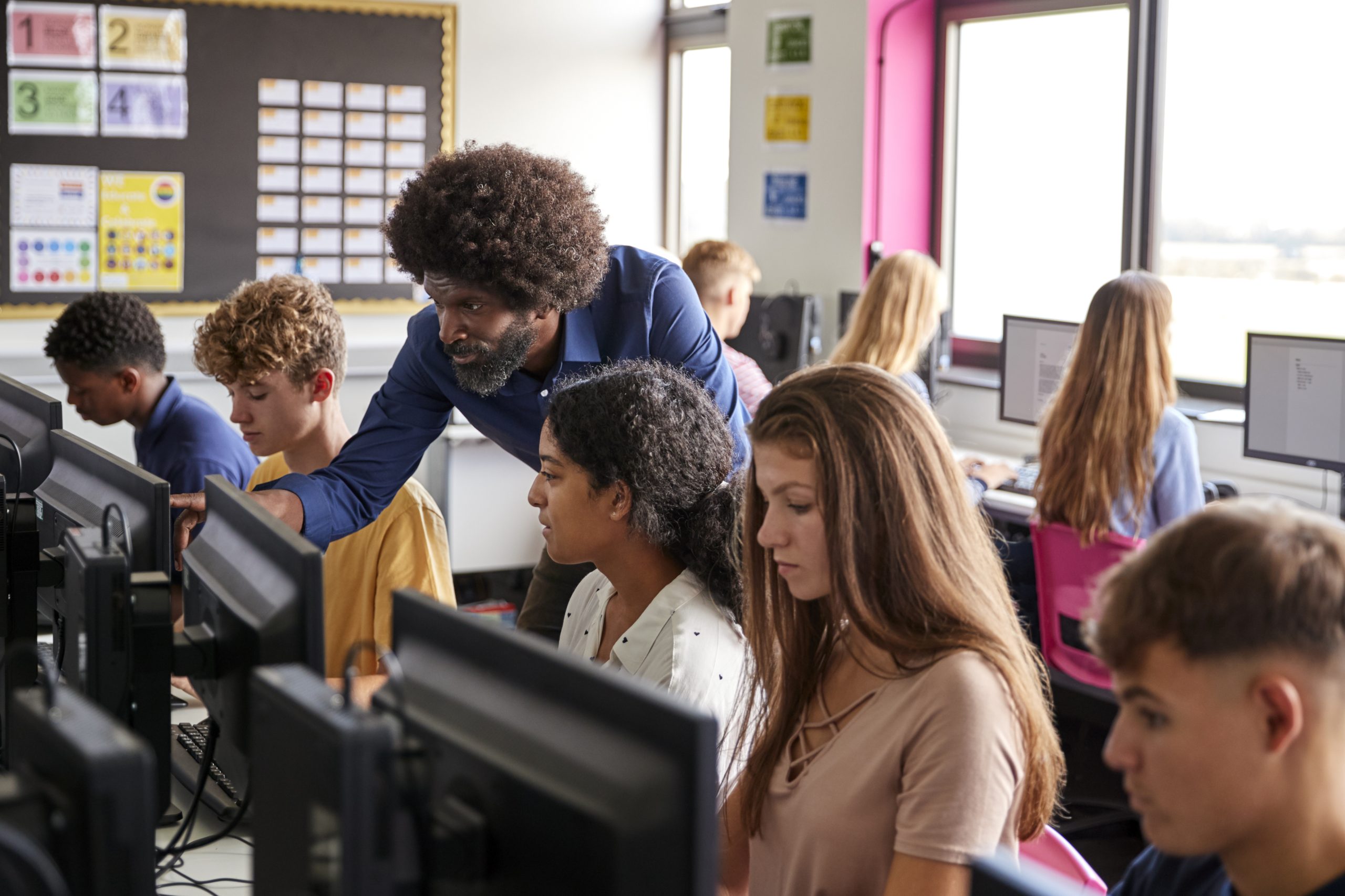 A teacher helping students in a computer classroom